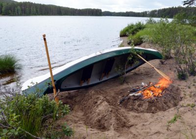 canoë déposé sur la rive de la rivière Örån et feu de camp pour le bivouac du soir